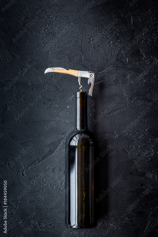 Open the wine. Corkscrew near bottle on black background top view copyspace Open the wine. Corkscrew near bottle on black background top view copyspace