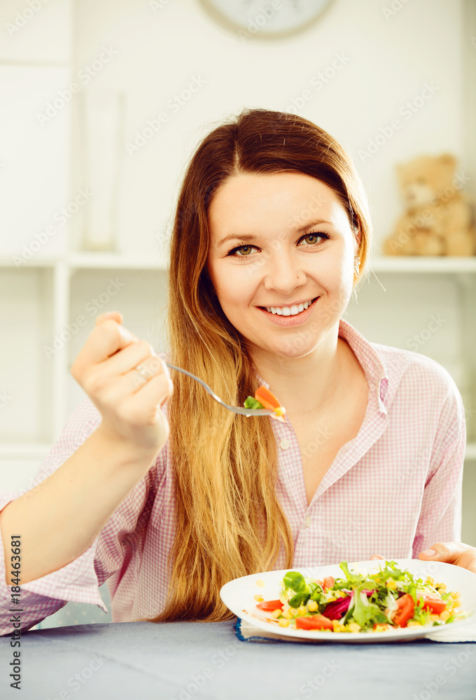 Young smiling girl enjoying tasty green salad