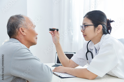 Female Doctor checking to senior man patient eyes. photo