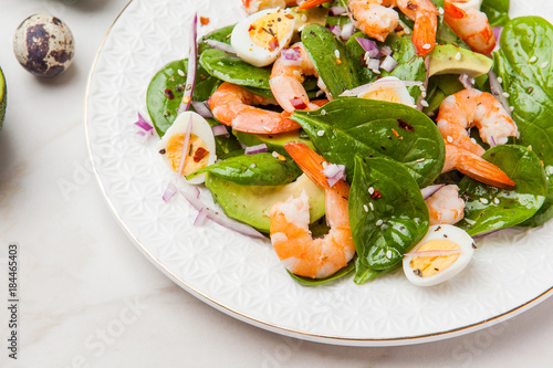 Fresh, healthy salad with shrimps, spinach and avocado on a marble table
