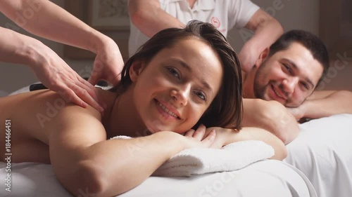Young couple is getting a relaxing massage from female masseurs in wellness center.