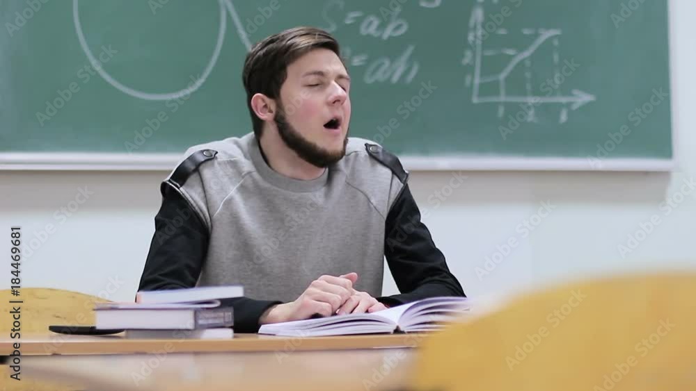 Tired student falling asleep in the classroom at the table Tired student falling asleep in the classroom at the table