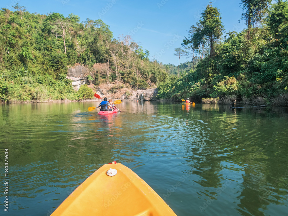 Obraz premium Tourists are kayaking to visit the waterfall in an atmosphere surrounded by mountains,places Wang Bon Reservoir, Nakhon Nayok, Thailand.