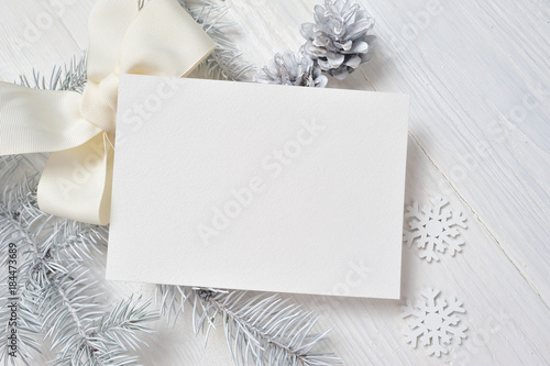 Mockup Christmas greeting card with white tree and cone, flatlay on a white wooden background, with place for your text