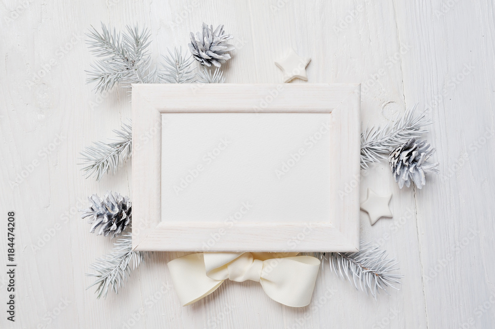 Fototapeta premium Mockup Christmas greeting card top view and white frame, flatlay on a white wooden background with a ribbon, with place for your text