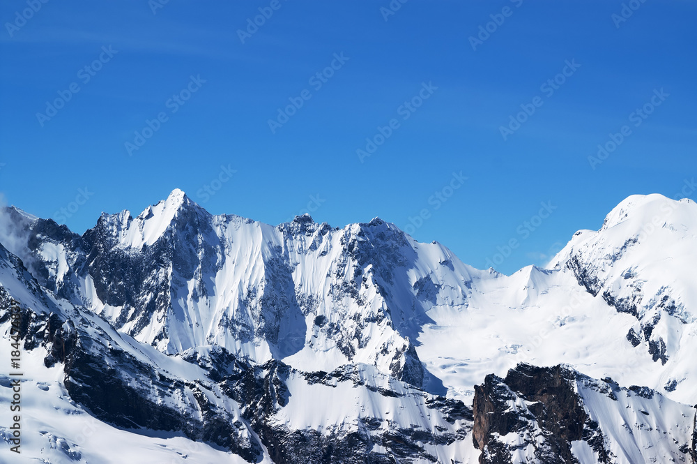Winter snowy mountains and beautiful blue sky in cold sun day