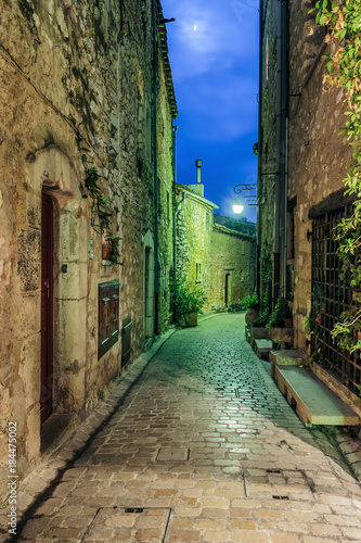 Narrow cobbled street with flowers in the old village at night, France.
