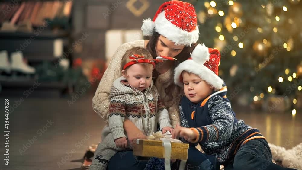 Family opening christmas present in front of tree Family opening christmas present in front of tree