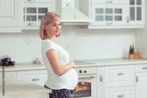Beautiful pregnant woman in white domestic kitchen