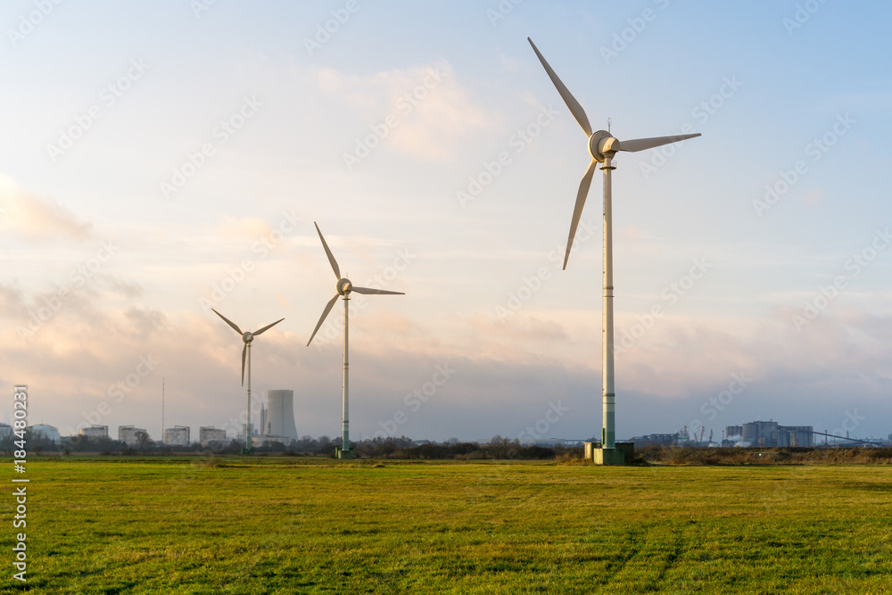Windräder auf einer Wiese mit Kohlekraftwerk im Hintergrund Windräder auf einer Wiese mit Kohlekraftwerk im Hintergrund