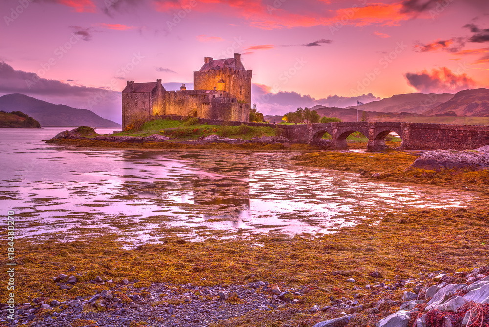 Magenta sunset at Eilean Donan Castle, Dornie, Kyle of Lochalsh in Scotland, United Kingdom. The most visited castle in the UK. Located on an island at the confluence of three sea lochs.