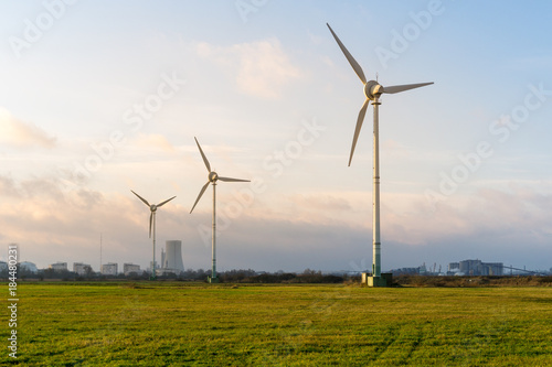 Windräder auf einer Wiese mit Kohlekraftwerk im Hintergrund