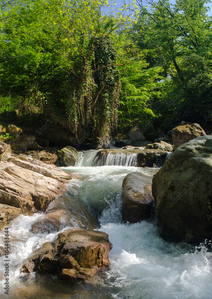 Naklejka premium Mały wodospad wśród skał na górskiej rzece.