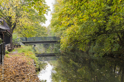 Autumn scene brilliant of fall color reflecting in small pond with bridge arching over water photo