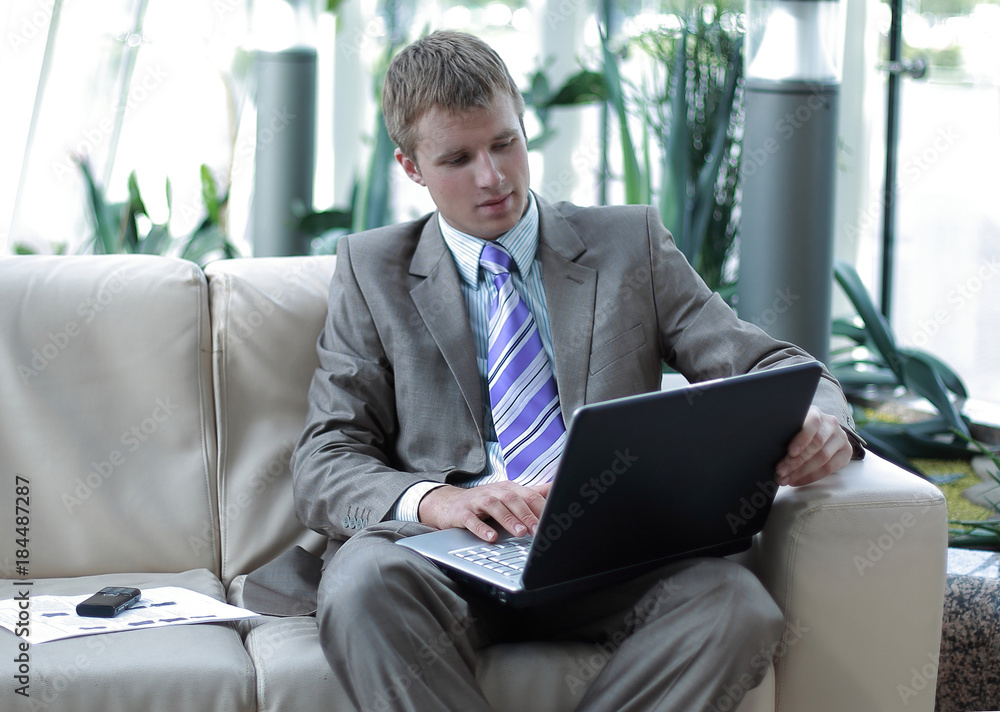 Happy successful businessman sitting on couch at office and working Happy successful businessman sitting on couch at office and working