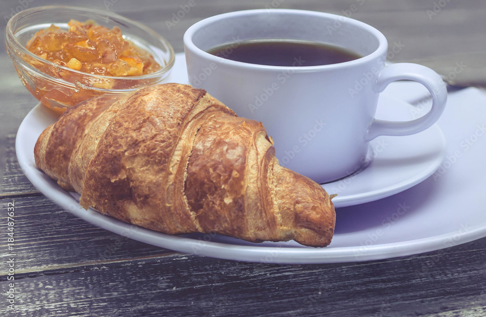 Croissant with orange jam and a cup of tea. Continental breakfast concept. Selective focus