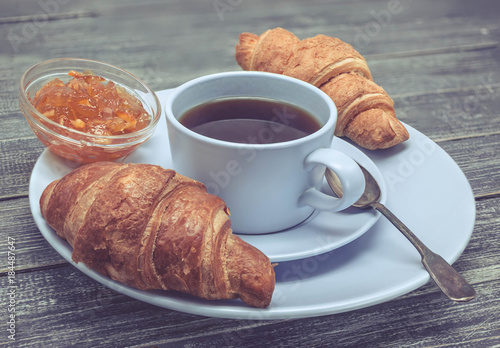 Fototapeta Naklejka Na Ścianę i Meble -  Croissant with orange jam and a cup of tea. Continental breakfast concept. Selective focus