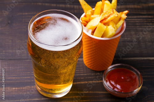 Beer with burger and fries on dark wooden background. Ale and food, horizontal