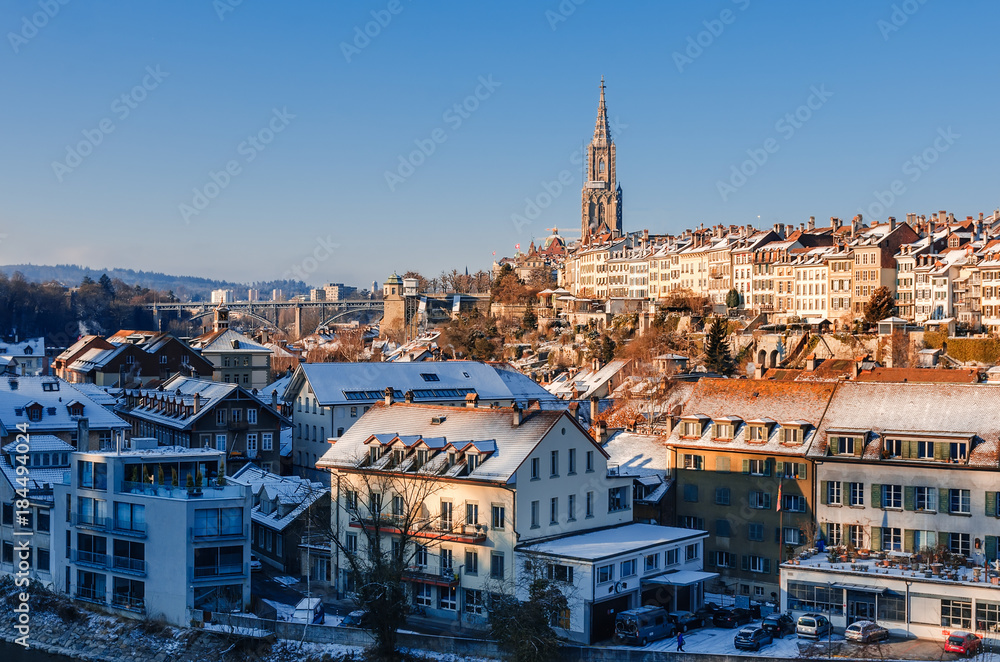 Panorama of snow-covered roofs of Bern's old town and Steeple of Berne Cathedral. Ancient cities of Europe in winter.