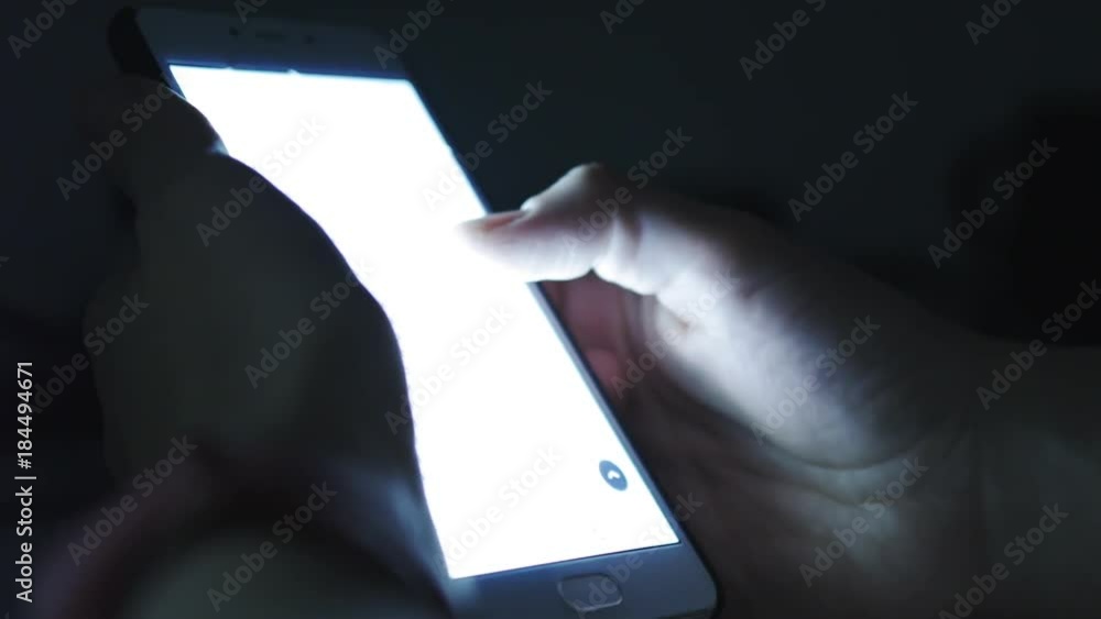 Close up of woman using smartphone in dark environment, her hand dimly lit by phone screen Close up of woman using smartphone in dark environment, her hand dimly lit by phone screen