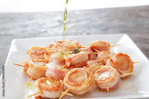 Adding oil to bacon wrapped scallops on plate photo