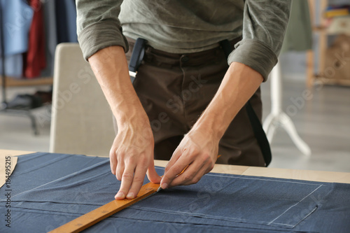 Young tailor working with textile in atelier