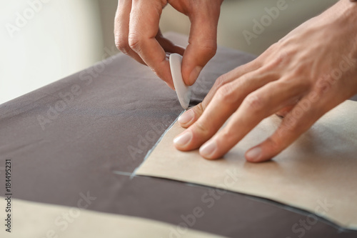 Young tailor working with sewing pattern, closeup