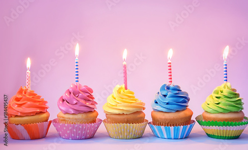 Delicious cupcakes with candles on color background