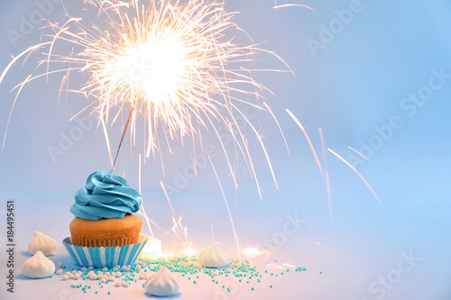 Delicious cupcake with sparkler on color background