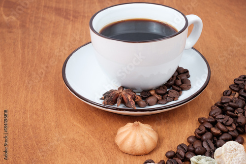 Coffee cup and beans, cinnamon sticks, on wooden table on background