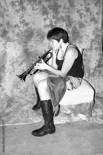 Female beauty playing her trumpet in a studio basement.