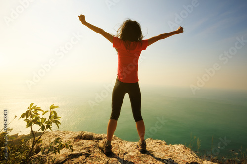 freedom female standing  with outstretched arms on sunrise windy coast