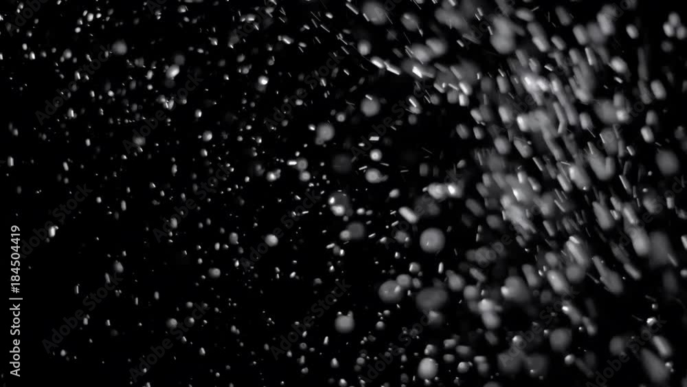 Several snow particles falling down over a black background that you ...