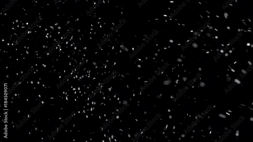 Several snow particles falling down over a black background that you ...