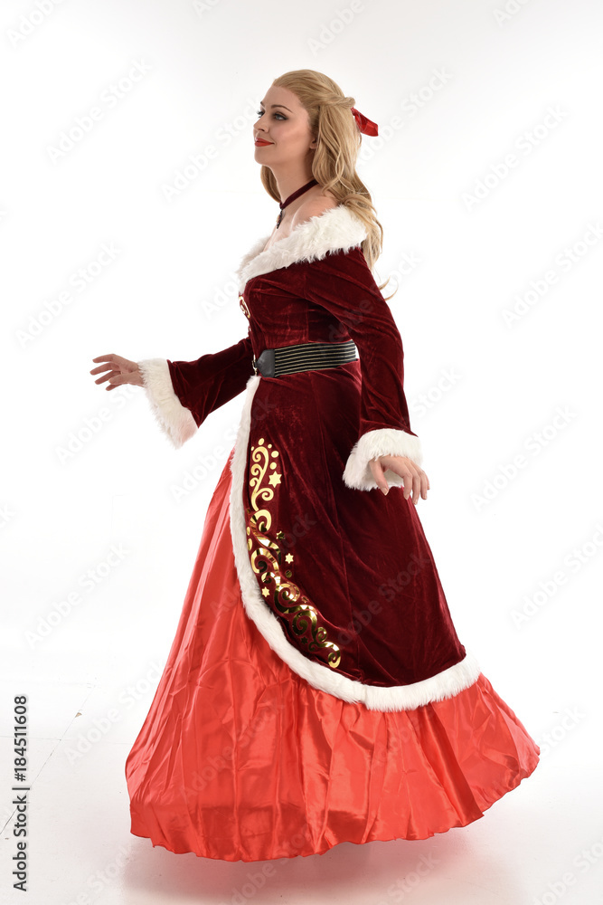 full length portrait of pretty blonde lady wearing red and white christmas inspired costume gown, standing pose on white background.
