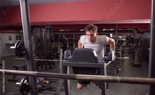 one young man, dip exercise, dark gym indoors. full lenght body shot.