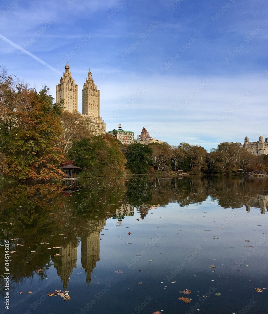Buildings in Manhattan reflect on lake at Central Park in autumn