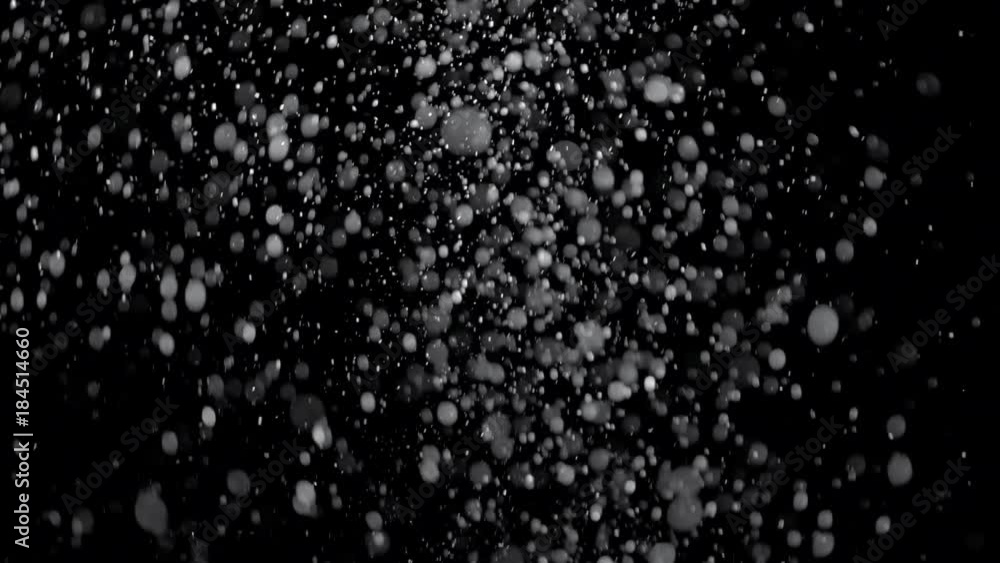 Several snow particles falling down over a black background that you ...