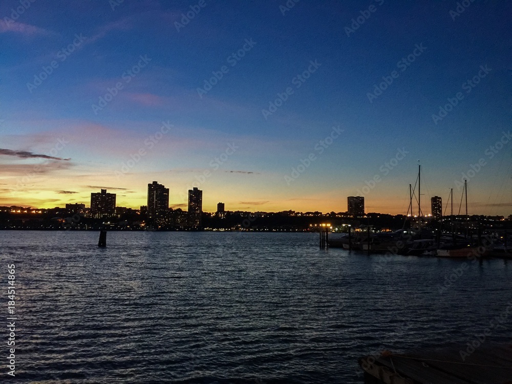 Silhouette city behind Hudson River with sunset sky