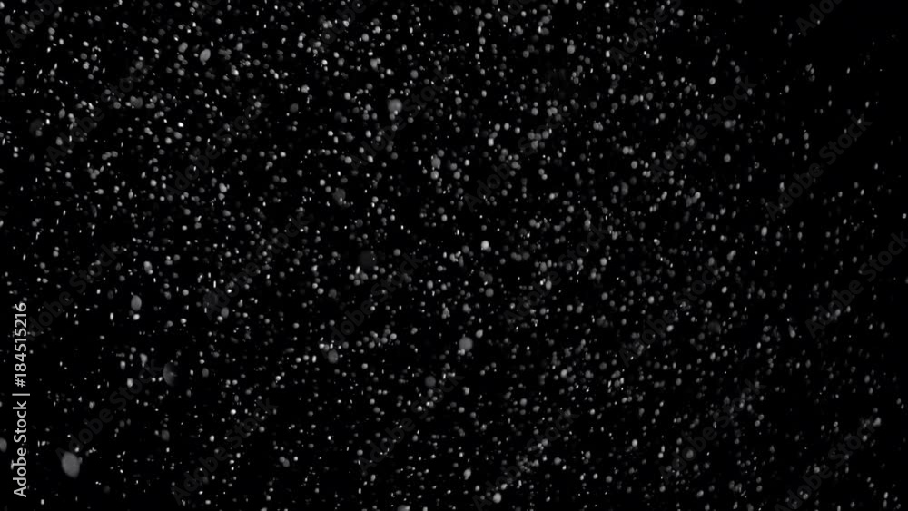 Several snow particles falling down over a black background that you ...