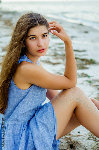 girl with a smile. Beautiful young woman in a blue dress. portrait of a beautiful cheerful girl. Portrait of a girl traveler. young woman sits on the beach. concept of freedom and happiness