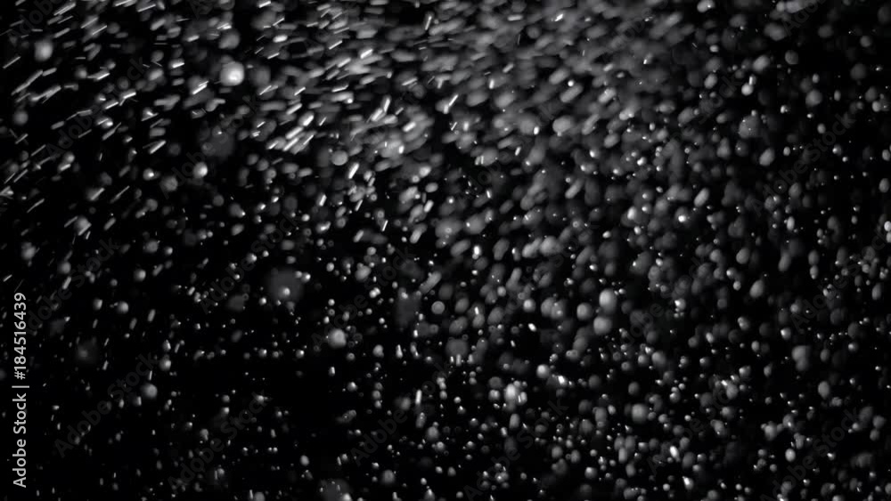 Several snow particles falling down over a black background that you ...