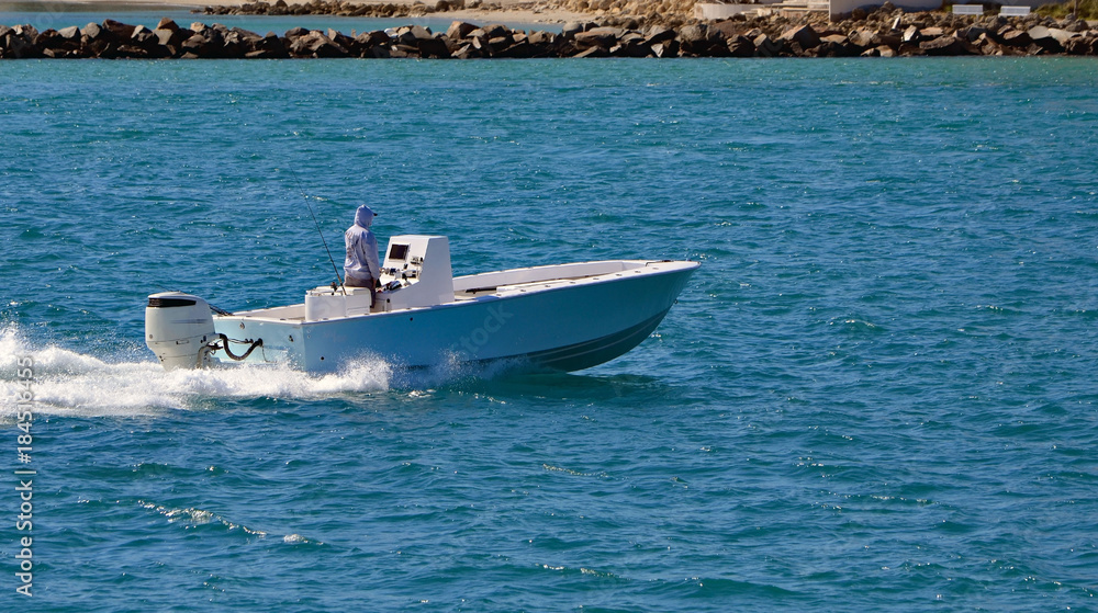 Open sport fishing boat powered by a single outboard engine cruising through Government Cut off Miami Beach,Florida Open sport fishing boat powered by a single outboard engine cruising through Government Cut off Miami Beach,Florida