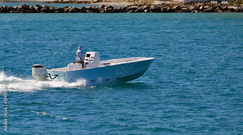 Open sport fishing boat powered by a single outboard engine cruising through Government Cut off Miami Beach,Florida