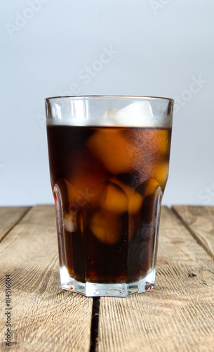 Glass with cola and ice on a wooden table