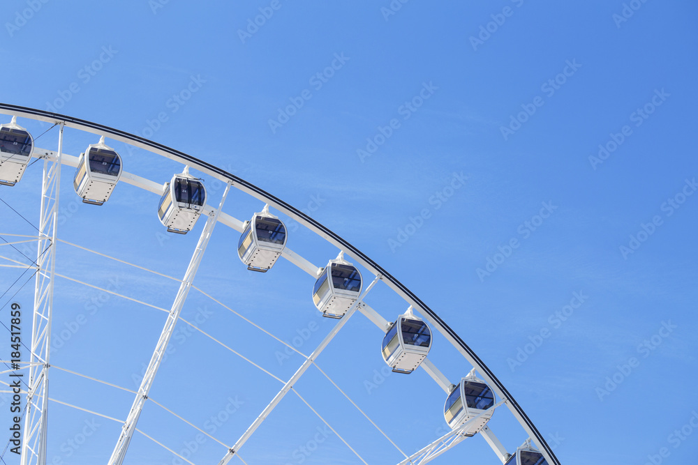 Giant Ferris wheel with numbered cabins in the park - Bright blue sky with sharp clouds behind it. - obrazy, fototapety, plakaty 