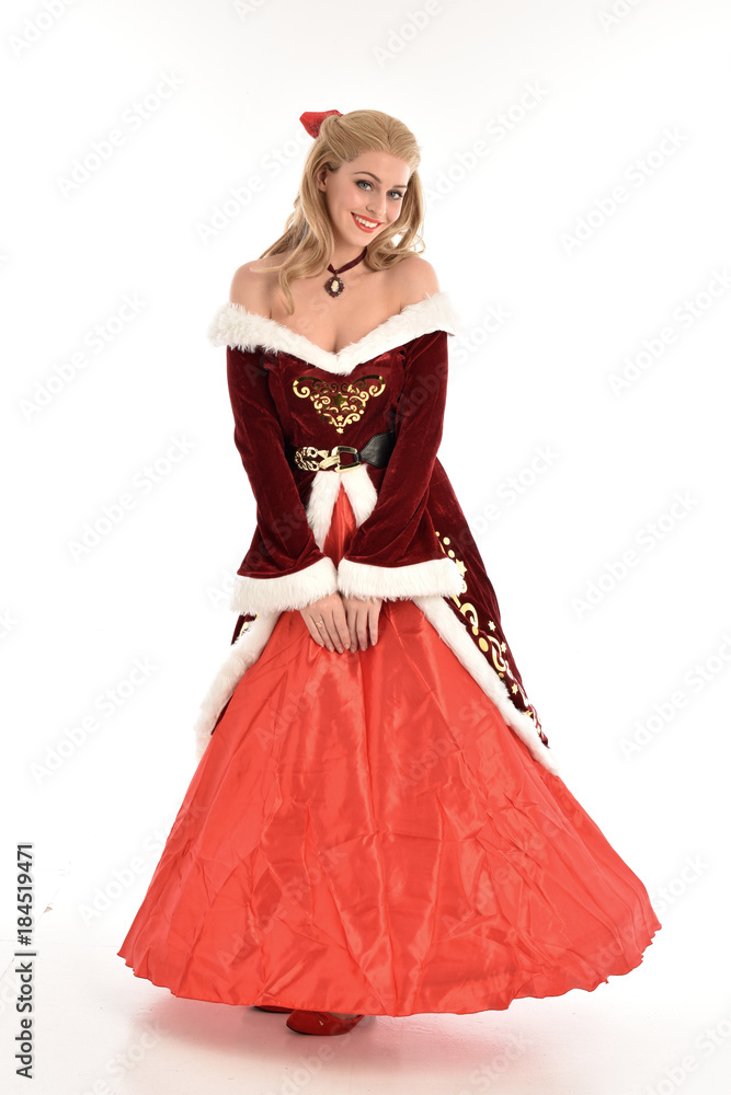 full length portrait of pretty blonde lady wearing red and white christmas inspired costume gown, standing pose on white background.