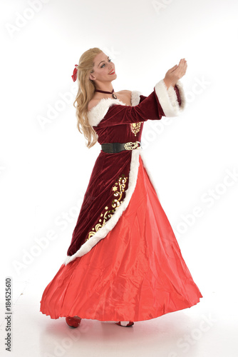 full length portrait of pretty blonde lady wearing red and white christmas inspired costume gown, standing pose on white background.