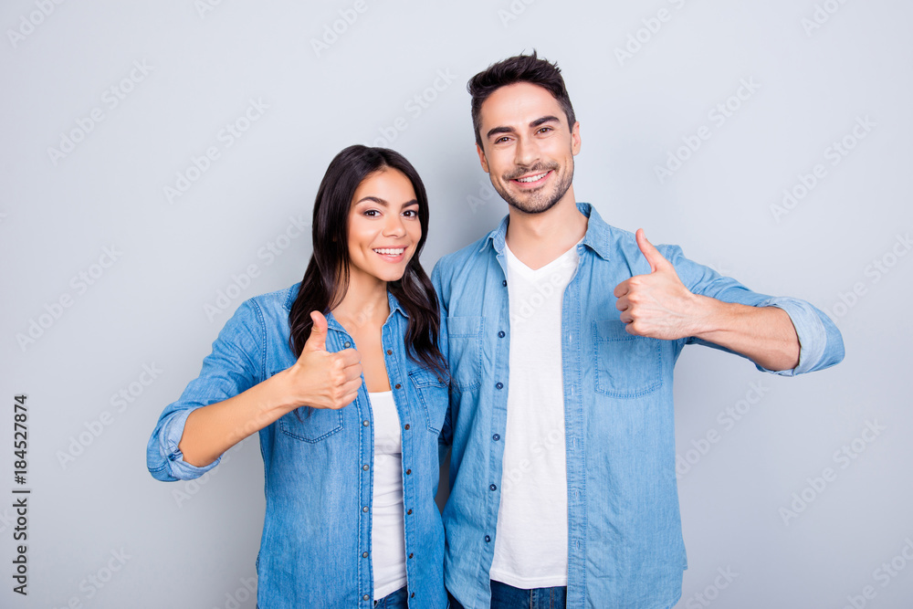 Sweet, attractive, smiling hispanic lovely cute couple in casual outfit showing thumb up sign over grey background Sweet, attractive, smiling hispanic lovely cute couple in casual outfit showing thumb up sign over grey background
