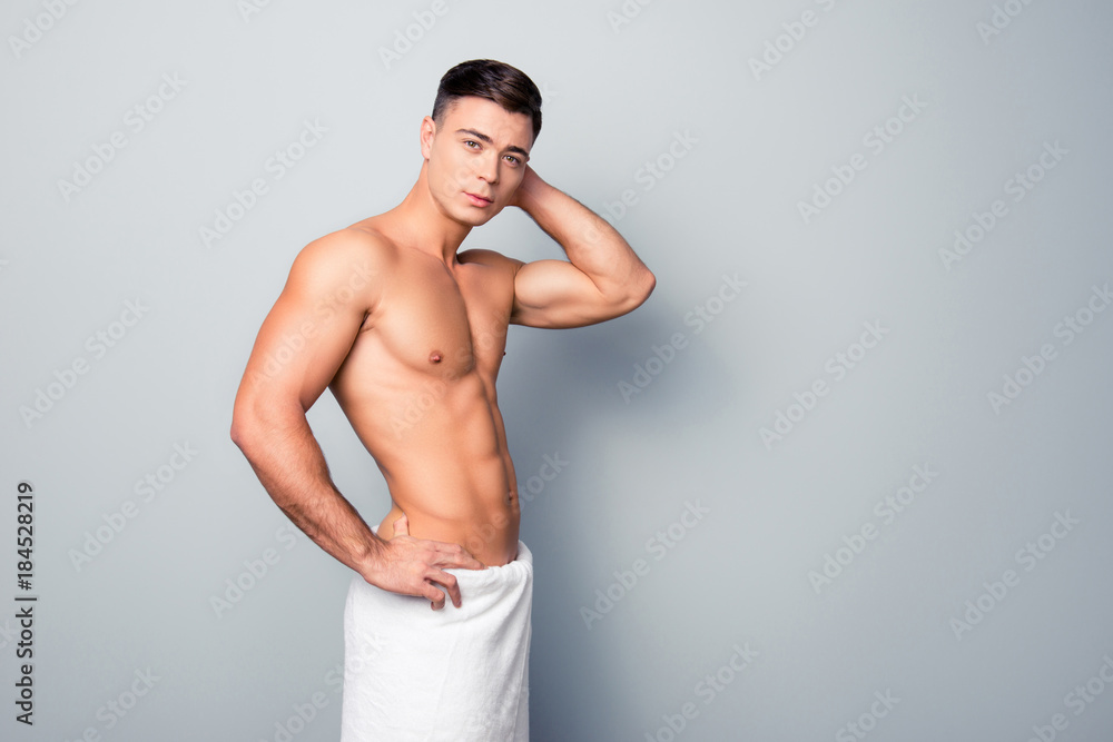 Portrait of sexy stunning handsome sporty athletic guy standing topless and  wearing a white towel on